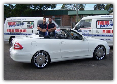 The Twins Performance mechanics with their vans and a convertible